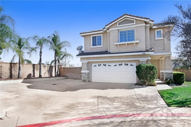 traditional-style house featuring driveway, an attached garage, fence, and stucco siding