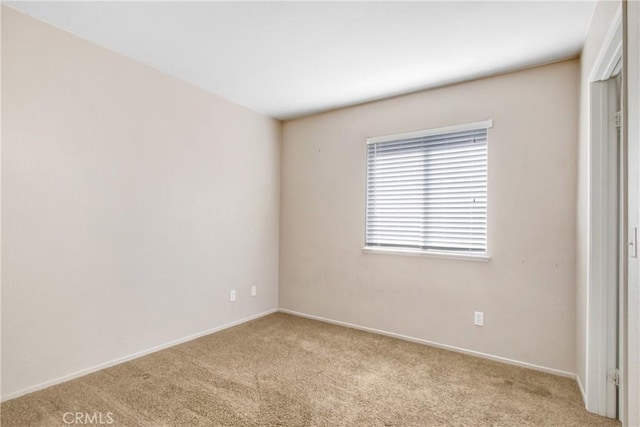 carpeted empty room featuring baseboards