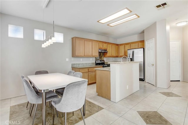 kitchen featuring a center island with sink, visible vents, light countertops, appliances with stainless steel finishes, and under cabinet range hood