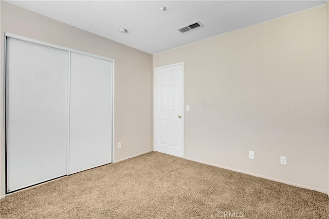 unfurnished bedroom with visible vents, a closet, and light colored carpet