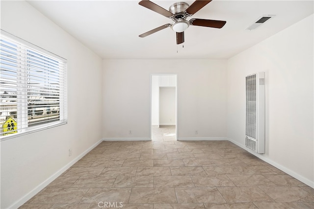 unfurnished room featuring a ceiling fan, a heating unit, visible vents, and baseboards