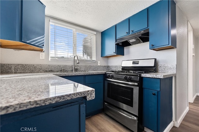 kitchen with blue cabinets, under cabinet range hood, stainless steel gas range, and a sink