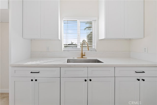 kitchen featuring light stone countertops, white cabinetry, and a sink