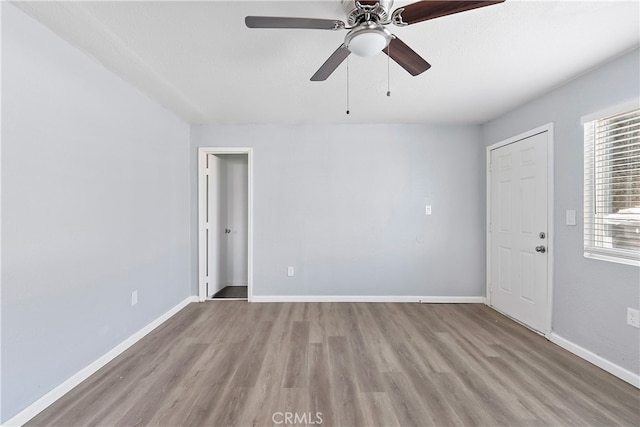 spare room featuring ceiling fan, baseboards, and wood finished floors