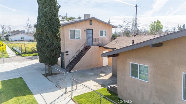 view of front of property featuring stucco siding, concrete driveway, fence, cooling unit, and stairs