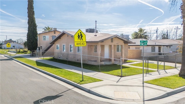 view of front facade featuring a fenced front yard, a residential view, a front lawn, and stucco siding