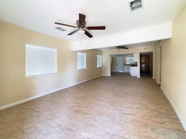 unfurnished living room featuring baseboards, visible vents, and a ceiling fan