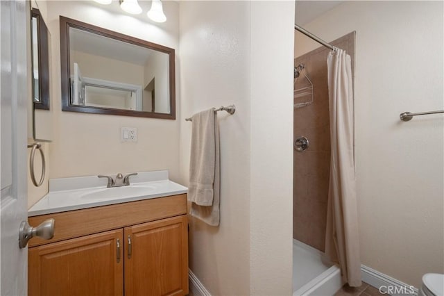 bathroom with a shower stall, baseboards, and vanity