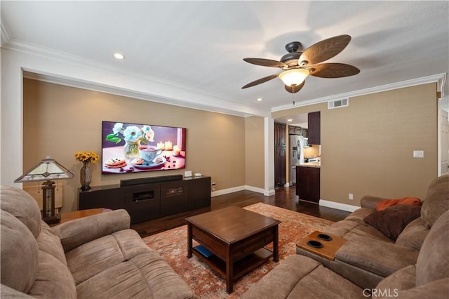 cinema room with ornamental molding, visible vents, baseboards, and wood finished floors