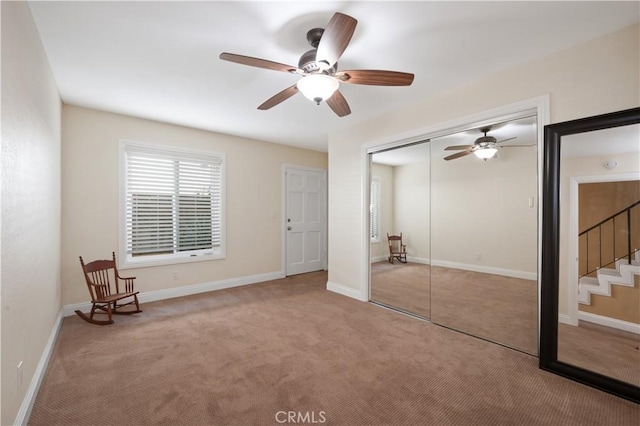 unfurnished bedroom featuring light carpet, ceiling fan, a closet, and baseboards