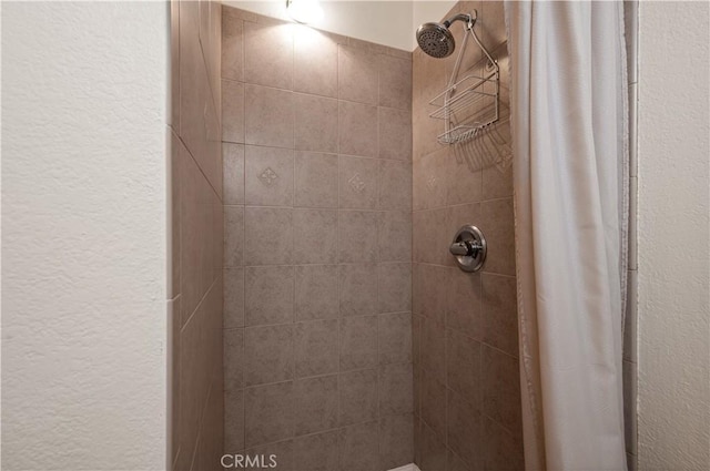 bathroom featuring a shower stall and a textured wall