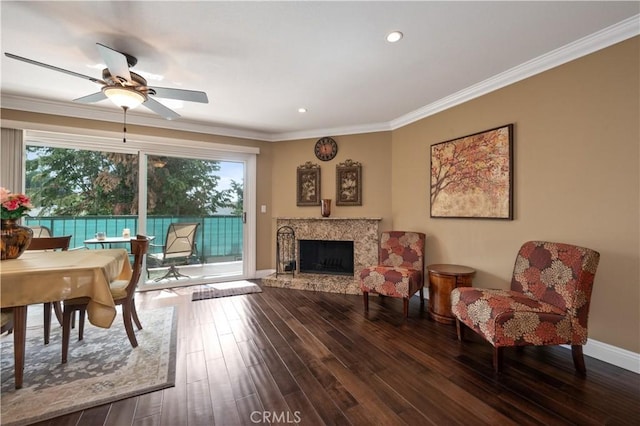 living area featuring ornamental molding, a fireplace, baseboards, and wood finished floors