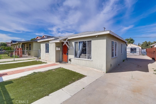 view of front of house with a front lawn, fence, and stucco siding