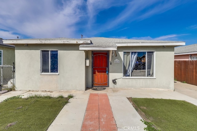 view of front facade with fence and stucco siding