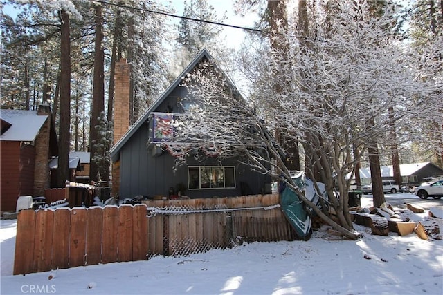 view of front facade with a chimney and fence