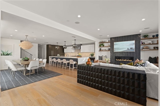 living area featuring light wood-type flooring, a tiled fireplace, and recessed lighting