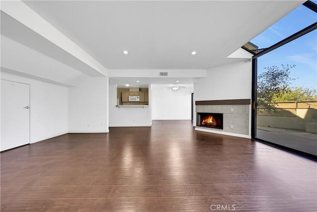 unfurnished living room with recessed lighting, a skylight, a fireplace, visible vents, and dark wood-style floors