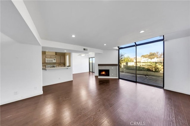 unfurnished living room featuring dark wood-style floors, a lit fireplace, recessed lighting, and floor to ceiling windows