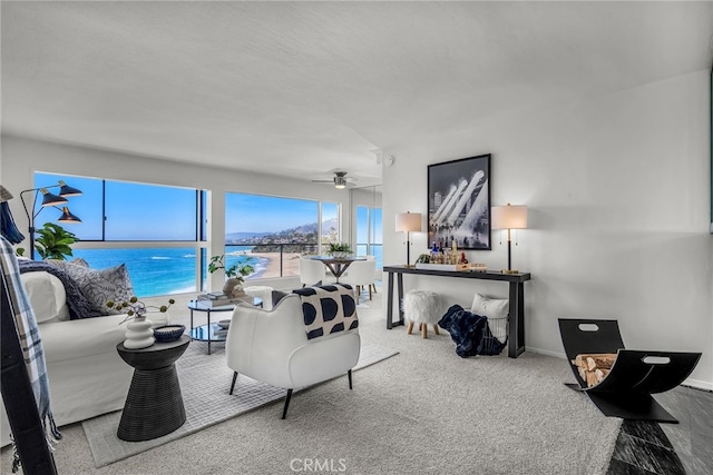 carpeted living room featuring a water view, ceiling fan, and baseboards