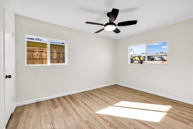 unfurnished room featuring light wood finished floors, baseboards, and a ceiling fan