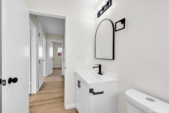 bathroom featuring toilet, wood finished floors, vanity, and baseboards