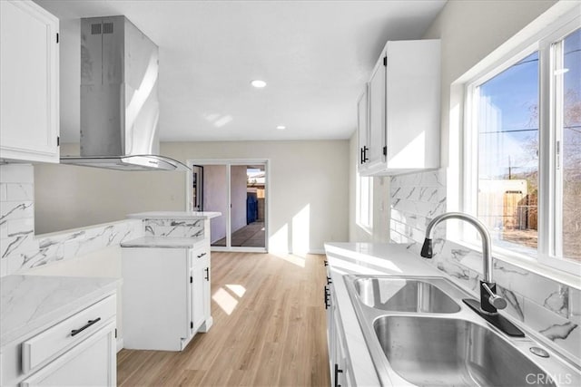 kitchen with range hood, white cabinetry, and a sink