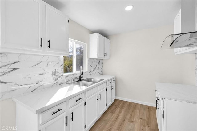 kitchen with light countertops, a sink, white cabinetry, and decorative backsplash