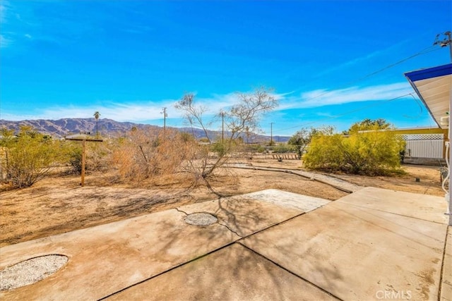 view of yard featuring a mountain view, fence, and a patio