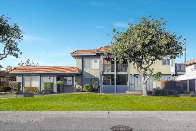 view of front of home with stucco siding, a front yard, and a tiled roof