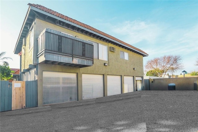 back of house featuring a gate, fence, a balcony, and stucco siding