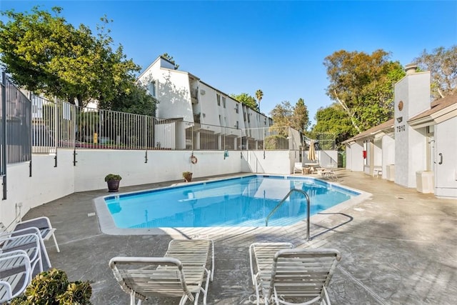 pool with a patio area and fence