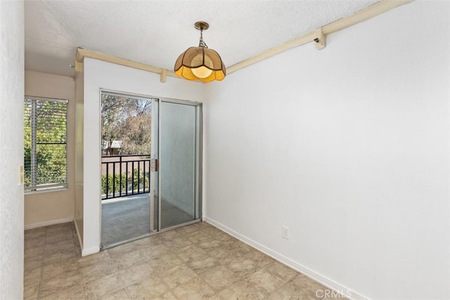 spare room with a textured ceiling and baseboards