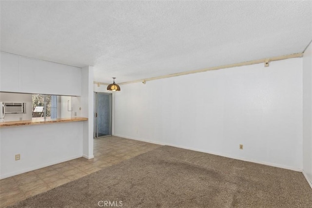 unfurnished room featuring a wall mounted air conditioner, baseboards, a textured ceiling, and carpet flooring