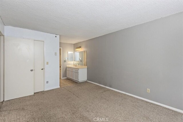 7506 Parkway Dr Unit 104, La Mesa, CA 91942 - unfurnished bedroom with light carpet, a textured ceiling, ensuite bath, baseboards, and a closet
