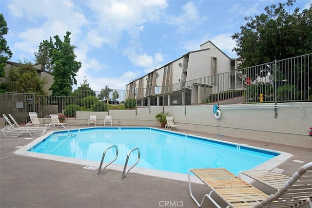 community pool with a patio area and fence