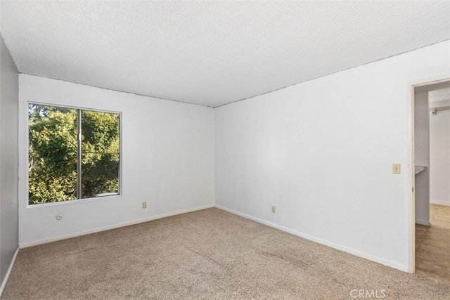 spare room featuring a textured ceiling, carpet, and baseboards