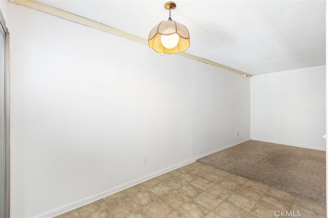 spare room with a textured ceiling, light floors, and baseboards