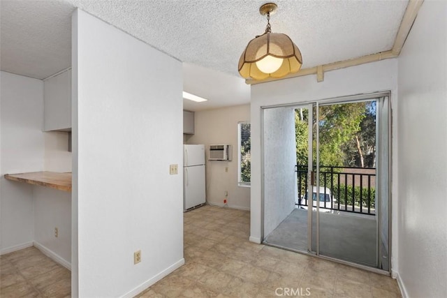 doorway to outside with baseboards, a textured ceiling, and a wall mounted air conditioner