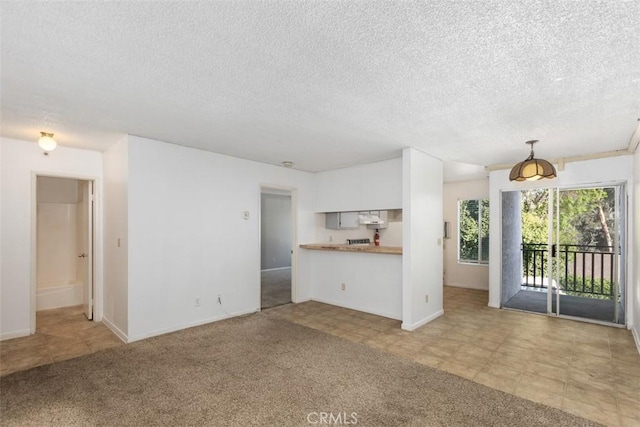 unfurnished living room featuring light colored carpet, a textured ceiling, and baseboards