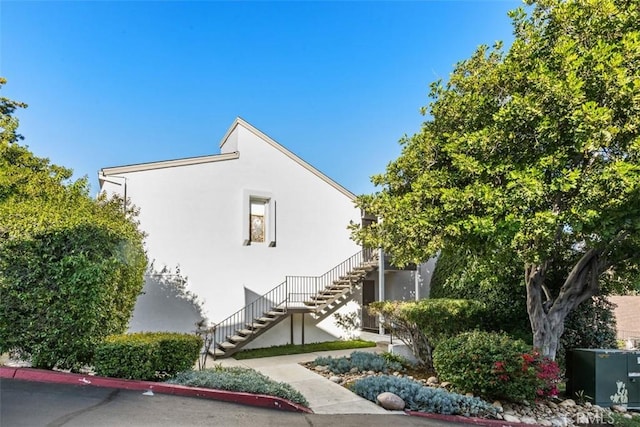 view of side of property with stairway and stucco siding