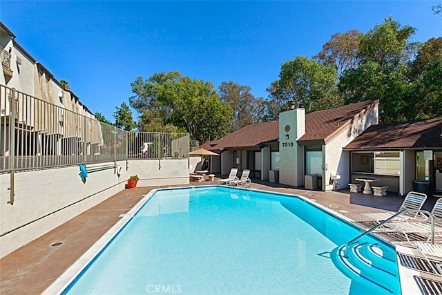 community pool with fence and a patio