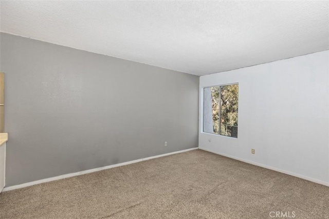 carpeted spare room with a textured ceiling and baseboards