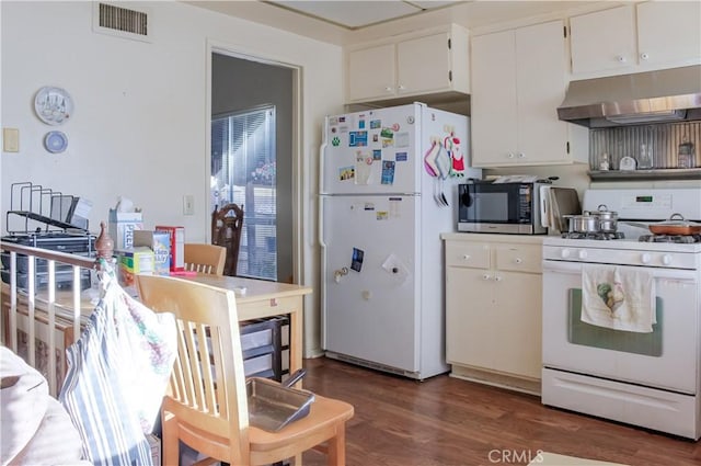 kitchen featuring white appliances, visible vents, white cabinets, wood finished floors, and under cabinet range hood