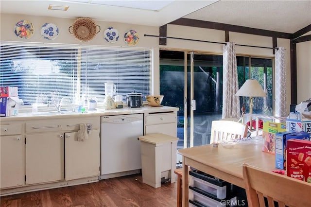 kitchen with white dishwasher, a sink, wood finished floors, white cabinets, and light countertops