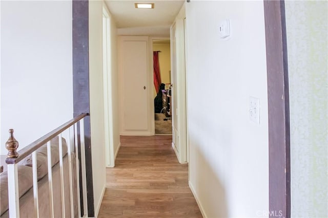 corridor with light wood-type flooring and baseboards