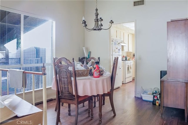 dining room with wood finished floors, visible vents, and an inviting chandelier