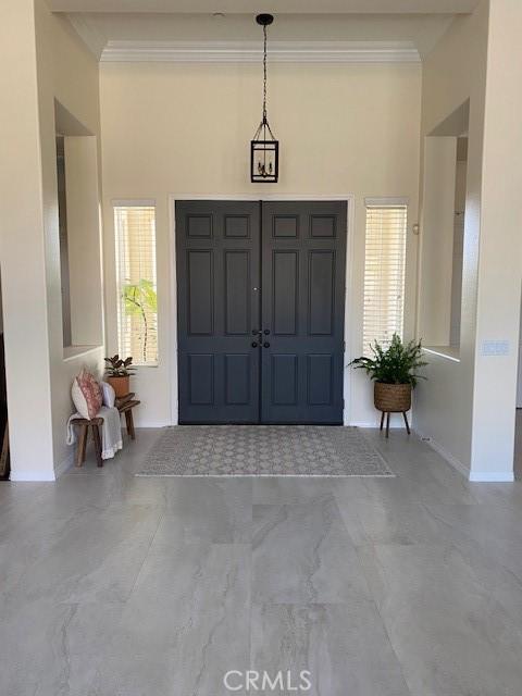 entrance foyer with baseboards and crown molding