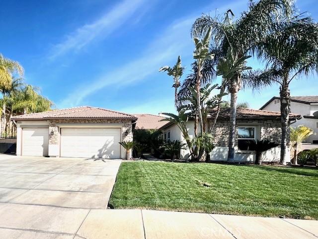 single story home featuring a garage, driveway, a tiled roof, and a front lawn