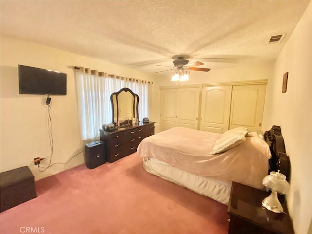 bedroom with a textured ceiling, ceiling fan, carpet flooring, visible vents, and a closet