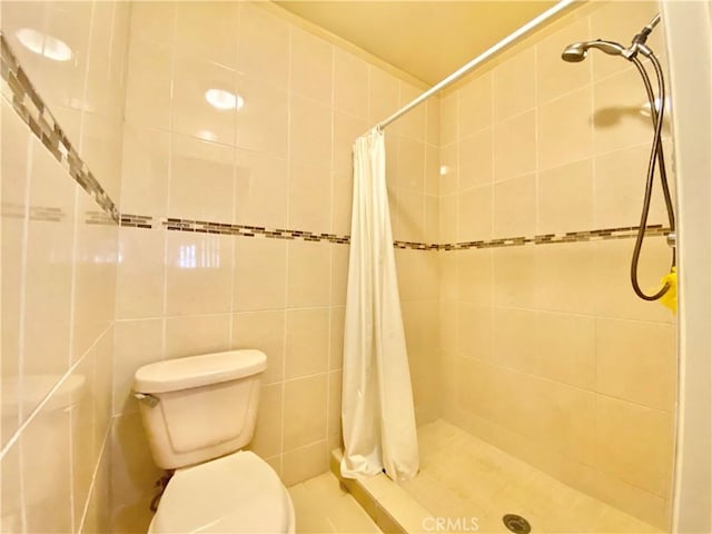 bathroom with toilet, a stall shower, and tile walls